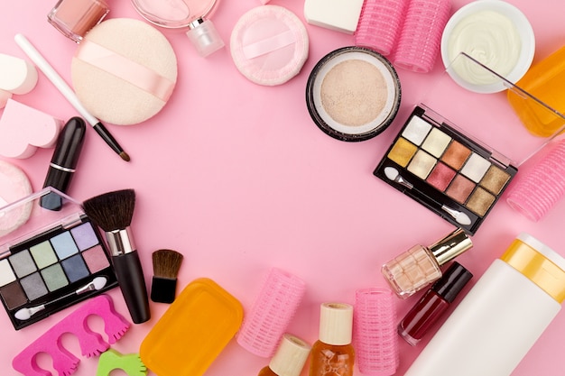 Belleza Spa Concepto Femenino. Diferentes Maquillaje Beauty Care Essentials Cosméticos en Flat Lay Pink Background. Vista superior. Encima.
