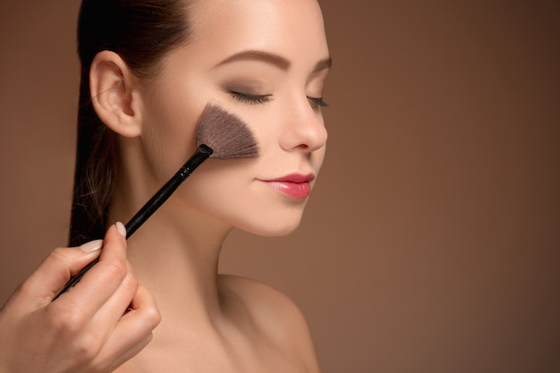 Foto gratuita bellezas con pincel de maquillaje. piel perfecta. aplicar maquillaje