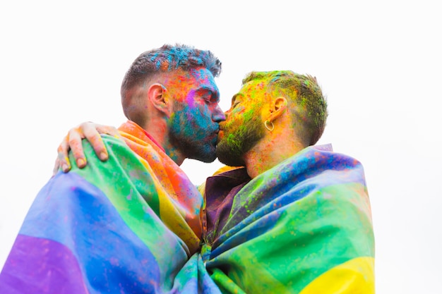 Beso desordenado pareja gay envolviendo en banderas de arcoiris