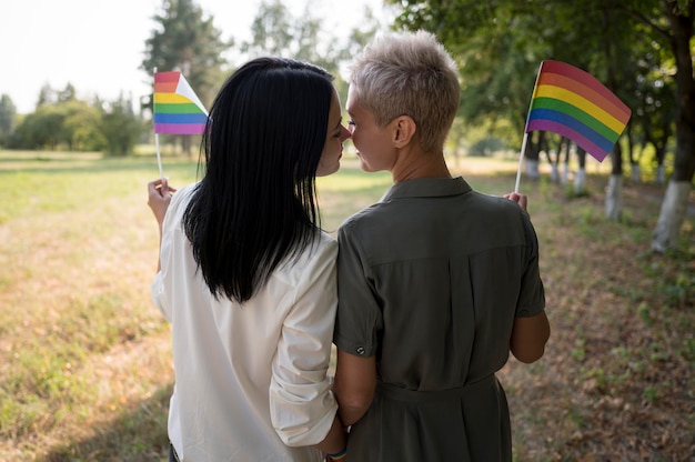 Beso de pareja de lesbianas sosteniendo la bandera