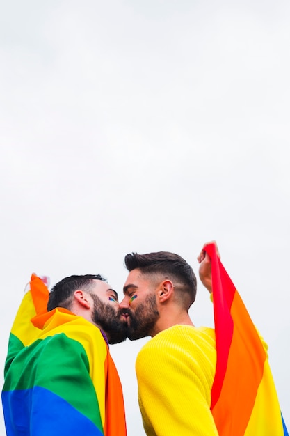 Besos de pareja de homosexuales cubiertos con banderas LGBT