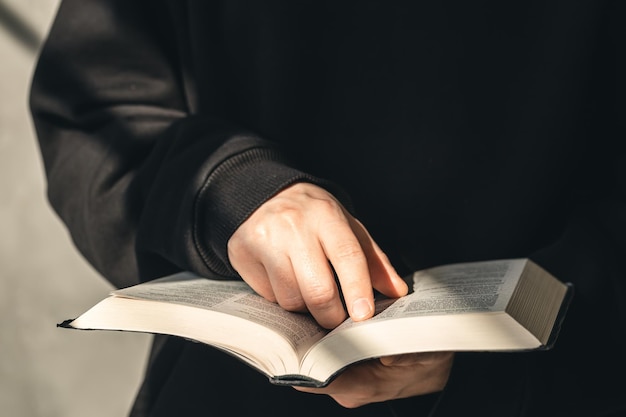 Biblia de libro abierto en primer plano de manos masculinas