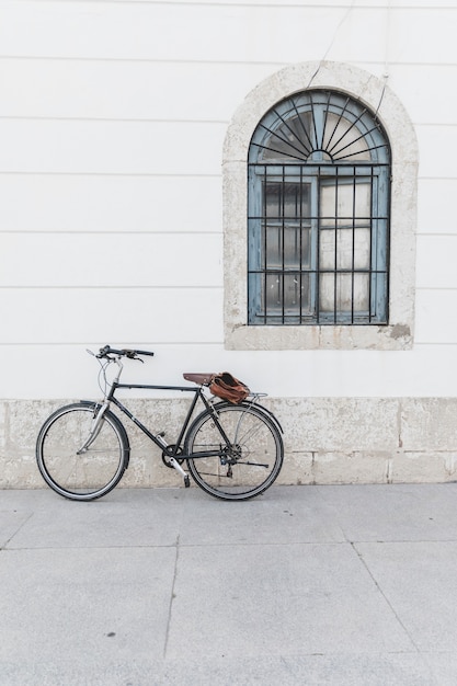 Bicicleta aparcada en pared blanca con ventana