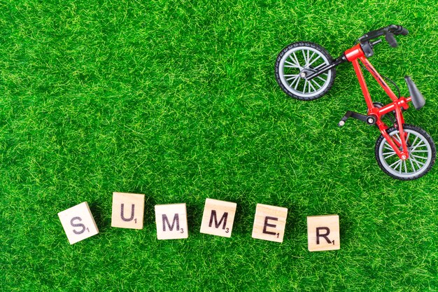 Bicicleta de juguete y letras sobre hierba.