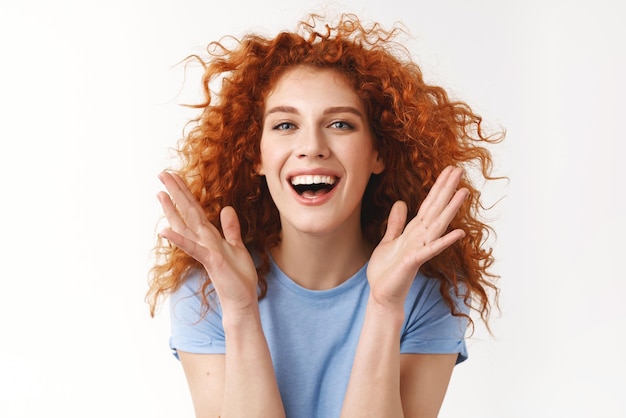 Bienestar de belleza y concepto de cuidado del cabello Seductora mujer joven alegre y despreocupada con un corte de pelo rizado rojizo flotando en el aire riéndose felizmente disfrutar del verano aplaudir manos entusiastas sonriendo con dientes