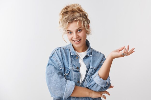 Bienestar, concepto de estilo de vida de felicidad. Atractiva elegante glamour despreocupada rubia mujer de pelo rizado ojos azules sonriendo alegremente hablando gesticulando palma levantada mirada relajada, encantada, optimista estado de ánimo