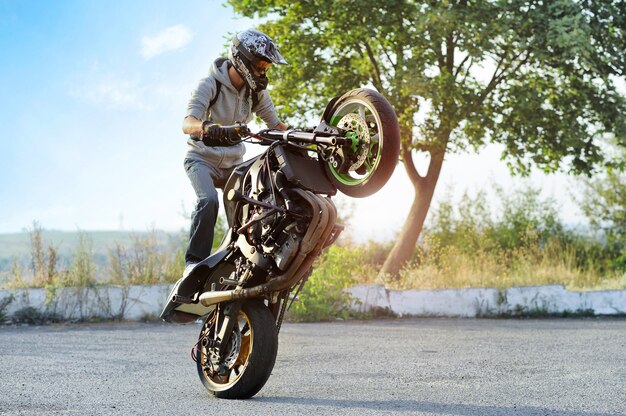 Biker haciendo trucos en motocicleta deportiva en la calle