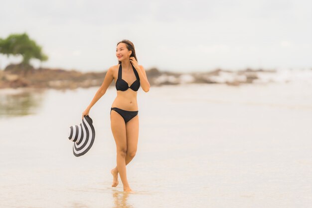 Bikini asiático joven hermoso del desgaste de mujer del retrato en el océano del mar de la playa