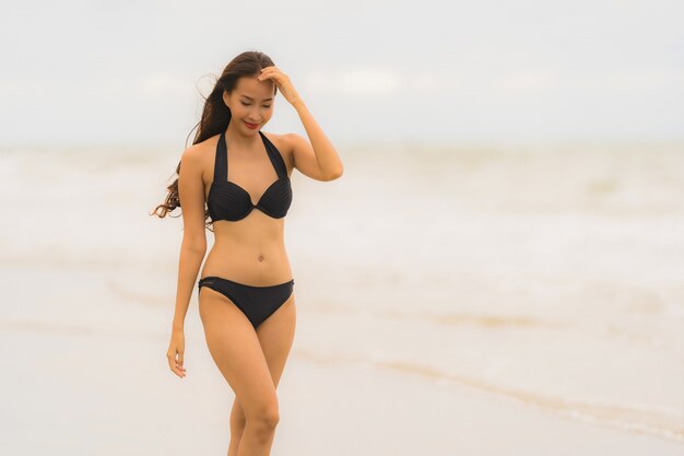 Bikini asiático joven hermoso del desgaste de mujer del retrato en el océano del mar de la playa