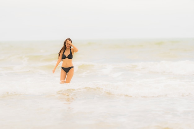 Bikini asiático joven hermoso del desgaste de mujer del retrato en el océano del mar de la playa