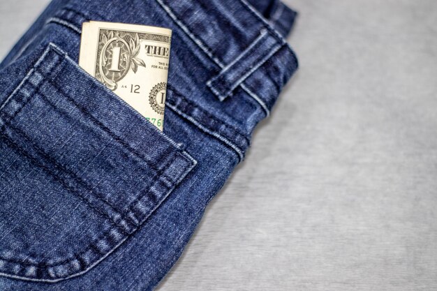 Billete de un dólar en el bolsillo de los pantalones vaqueros, ropa para niños, concepto de dinero, ahorro, educación financiera