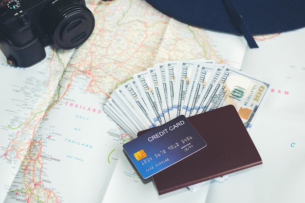 Billetes de dólar, tarjeta de crédito, pasaporte, cámara y sombrero azul