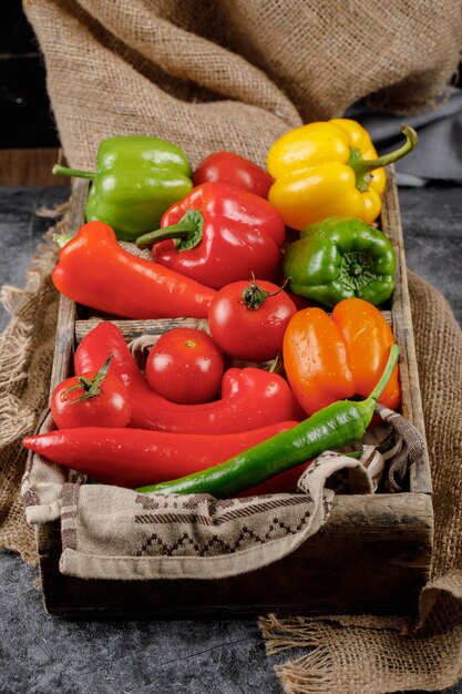 Bio pimientos y tomates en una bandeja de madera.