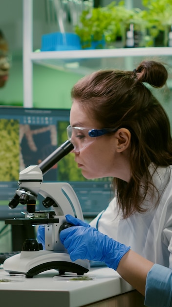 biólogo tomando muestra de hoja poniendo en microscopio observando líquido químico