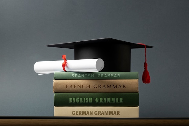 Foto gratuita birrete y diploma en libros de gramática
