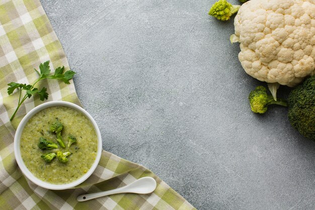 Bisque de brócoli plano sobre toalla de cocina y coliflor con espacio de copia