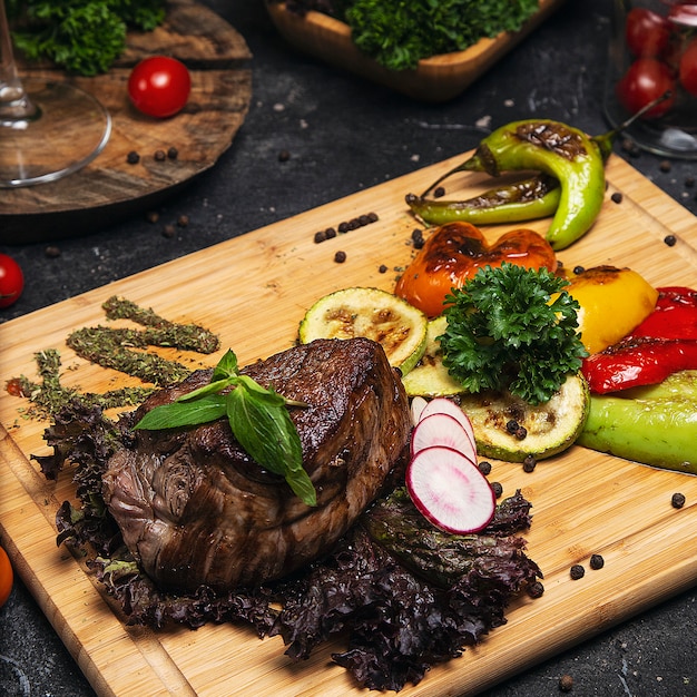 Bistec de buey con salsa de pimienta y verduras a la parrilla en una tabla de cortar