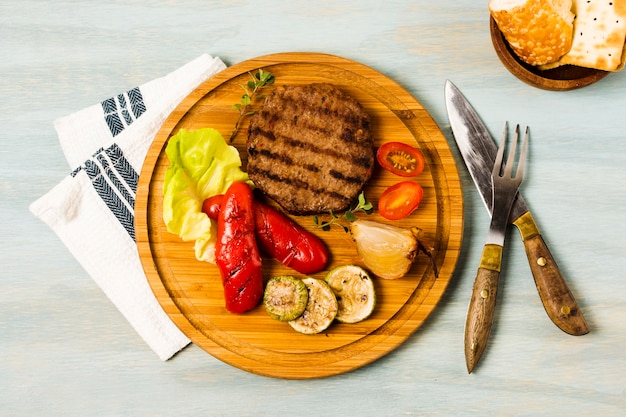 Bistec a la parrilla y verduras que se sirven en bandeja de madera