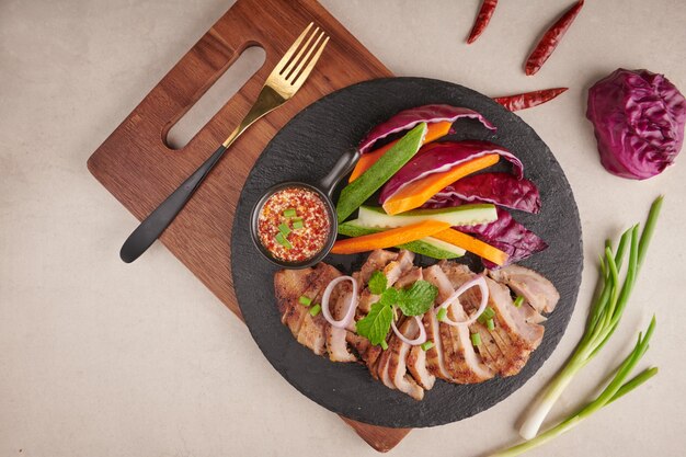 Bistec a la plancha con mezcla de verduras y especias. Comida sabrosa casera. superficie de piedra. Filete de cerdo con ensalada. La carne de cerdo a la parrilla es uno de los platos tailandeses más populares. Cerdo a la plancha con salsa picante.