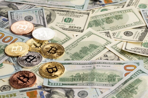 Bitcoin de diferentes colores sobre billetes de dólar