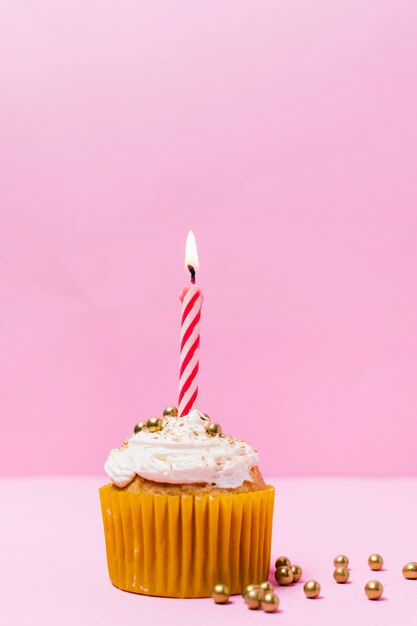 Bizcocho de cumpleaños con velas sobre fondo rosa