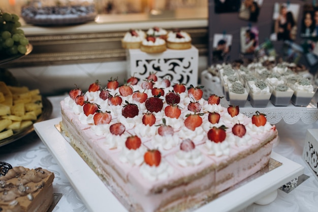 Bizcocho grande con crema y fresas cortadas en porciones