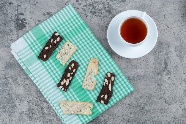 Bizcocho de pan delicioso con nueces y taza de té aromático en la superficie de mármol.