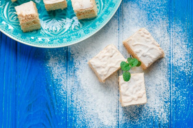 Bizcocho pastel de manzana pastila candy pastila decorado con hojas de menta en la tabla de cortar de madera azul