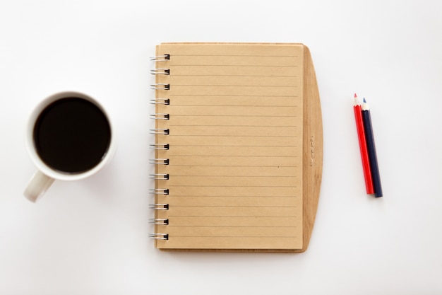 Blanco escritorio de oficina con un cuaderno y lápices, café