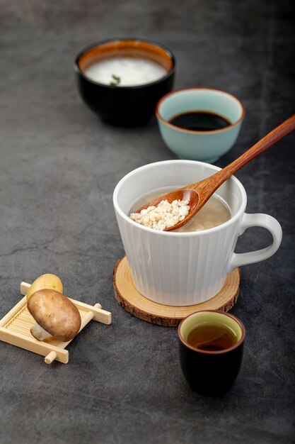 Blanco taza de sopa sobre un soporte de madera con un hongo