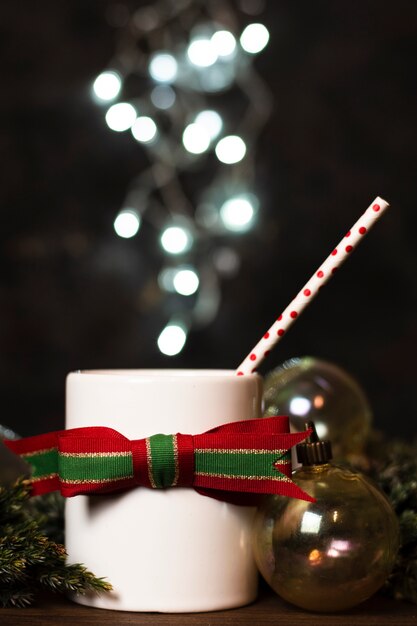 Blanco taza de té con luces de navidad en el fondo