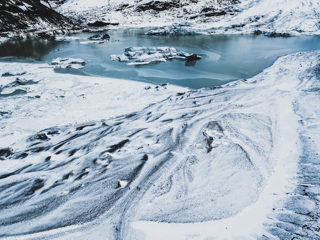 Blancos senderos nevados en las montañas escarpadas con un lago helado