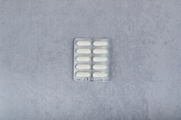 Un blister con pastillas blancas sobre superficie gris