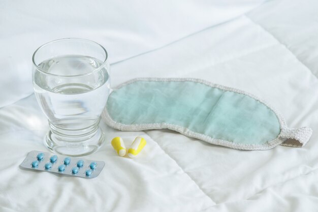 Blister de somníferos, venda y vaso de agua.
