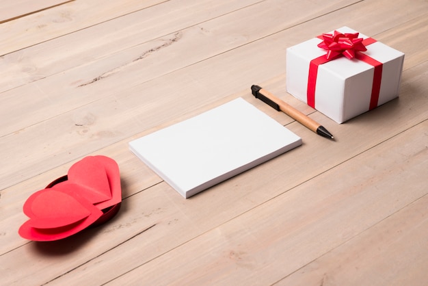 Bloc de notas en blanco con caja de regalo en la mesa