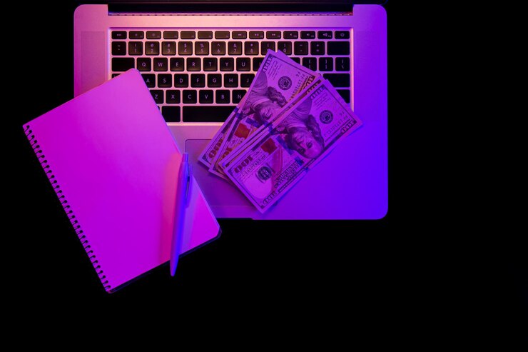 Foto gratuito bloc de notas en blanco para computadora portátil y papel moneda en la vista superior de iluminación de neón