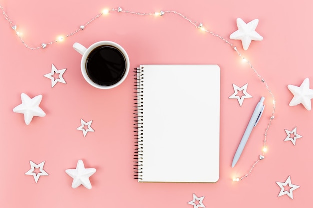 Foto gratuita bloc de notas en blanco sobre fondo rosa y estrellas decorativas y guirnaldas planas