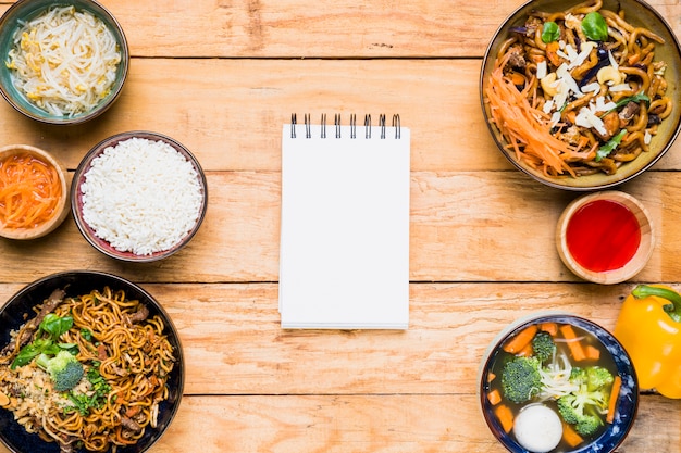 Bloc de notas espiral en blanco con comida tradicional tailandesa sobre la mesa de madera