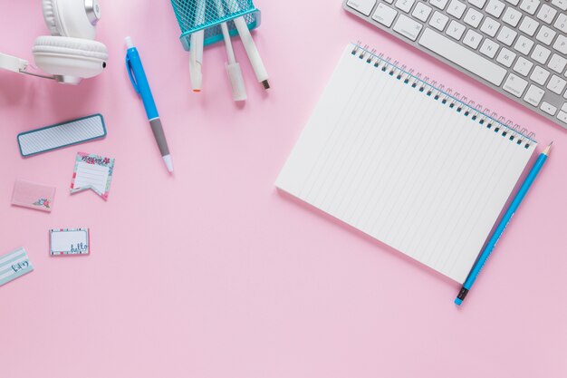 Bloc de notas espiral en blanco con efectos de escritorio y teclado sobre fondo rosa