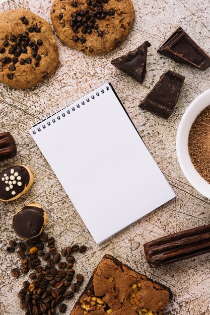 Bloc de notas entre granos de café, galletas y chocolates