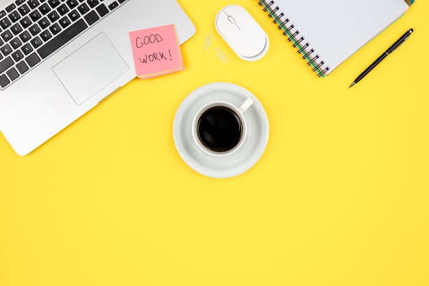 Foto gratuita bloc de notas portátil y taza de café en la vista superior de fondo amarillo