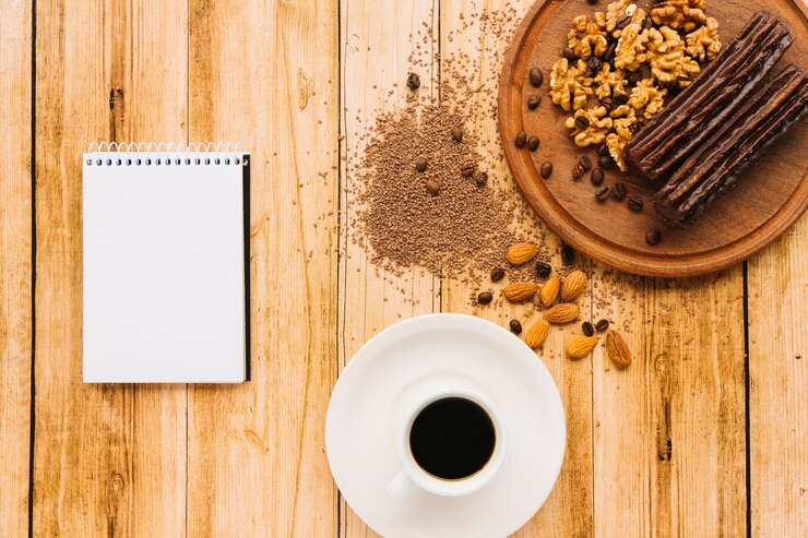 Foto gratuito bloc de notas y taza de café cerca de nueces en la tabla de cortar