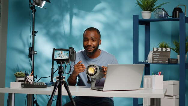 Blogger afroamericano revisando la luz del estudio en la cámara