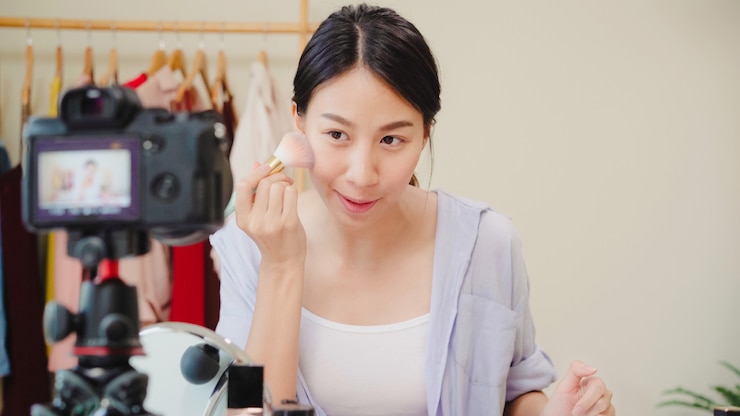 Foto gratuito la blogger de belleza presenta cosméticos de belleza que se sientan en la cámara frontal para grabar video.