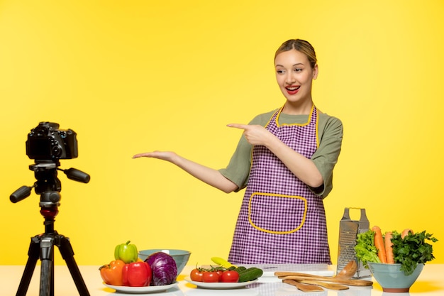 Blogger de comida adorable chef saludable grabando video para redes sociales apuntando a la izquierda