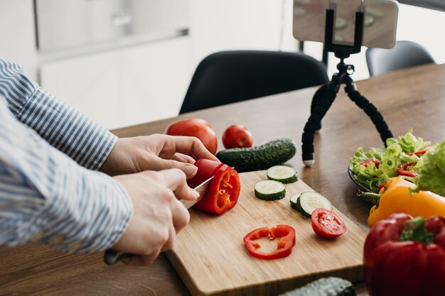 Blogger de comida femenina streaming con smartphone en casa mientras cocina