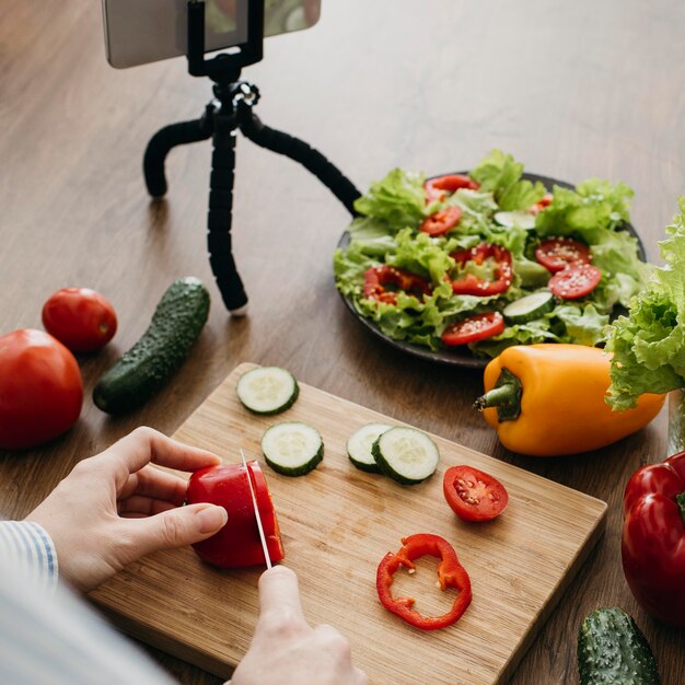 Blogger de comida femenina transmitiendo en casa con smartphone mientras cocina