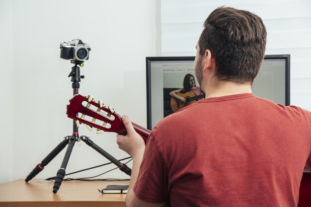 Blogger dando lecciones de guitarra desde el estudio de grabación de su casa