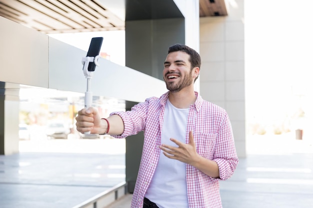 Blogger feliz grabando video en vivo en un teléfono inteligente en un centro comercial