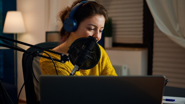 Blogger feliz leyendo mensajes de fanáticos que usan teléfonos inteligentes sentados en el estudio de podcasts en casa durante la transmisión en vivo, grabación. Programa en línea Producción en directo Presentador de transmisión por Internet que transmite contenido en vivo